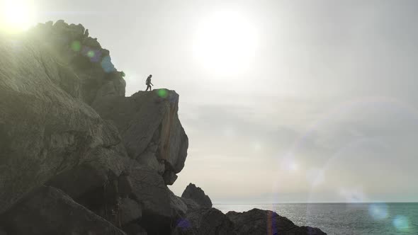 Male Tourist Got To the Edge of a Cliff and Enjoys a Panorama of the Sea and the Sky in Windy