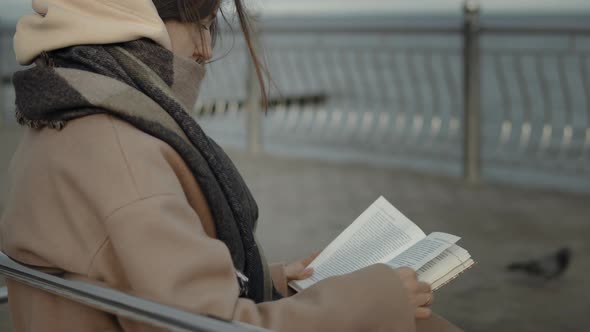 Woman Reading A Book On Embankment