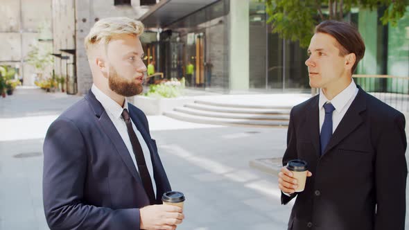 Confident businessman and his colleague in front of modern office building.