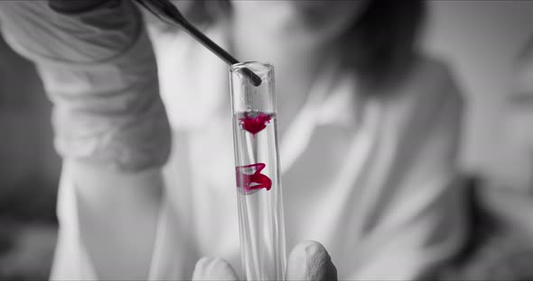 Scientist with Pipette Analyzes Red Colored Liquid To Extract the DNA