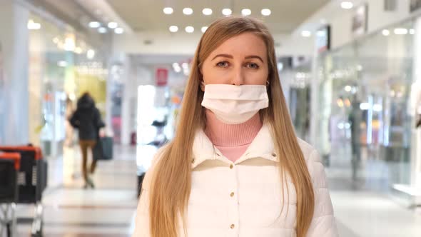 Upset woman in a medical mask in the mall. Mask protection against coronavirus