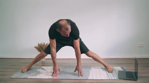 Caucasian Man Does Yoga Online Man on the Mat Trying to Get Up on the Splits Yoga for Beginners Fun