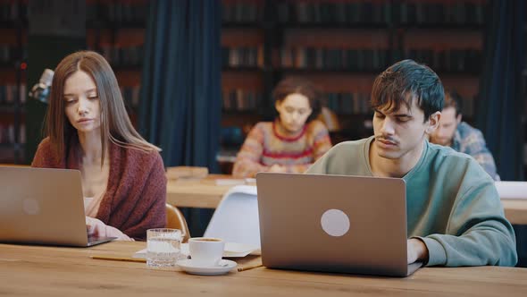 Concentrated Millennial Man and Woman Using Pc at University Library