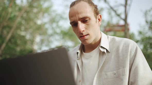 Pretty curly-haired man working on laptop