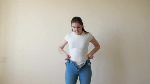 A Woman in a White t -Hirt Bounces Into Her Jeans and Struggles To Button Them