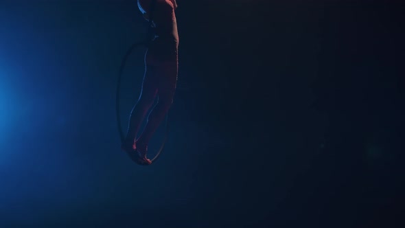 A Young Woman Gymnast Performs Acrobatic Stunts on an Air Hoop Under the Dome of a Circus