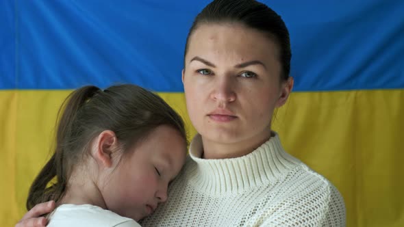 Young Woman with Her Daughter on the Background of the Flag of Ukraine