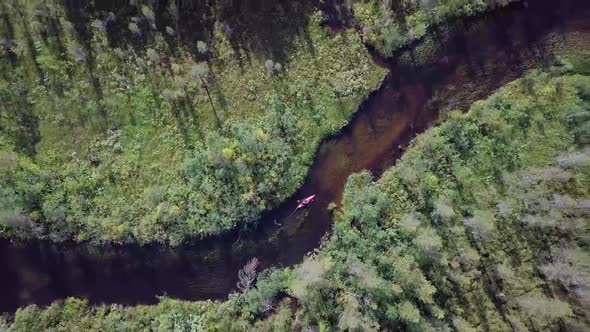 Aerial footage of a male in a red kayak paddling through a river in Lapland with beautiful views.