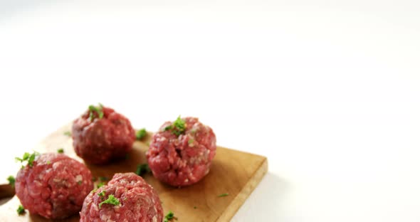 Raw meat balls on wooden board