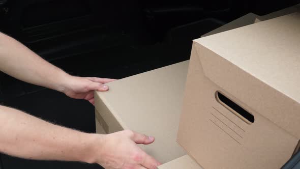 Close-up, Cardboard Boxes, Female and Male Hands. Couriers Unloading Parcels From Car Trunk. Cargo