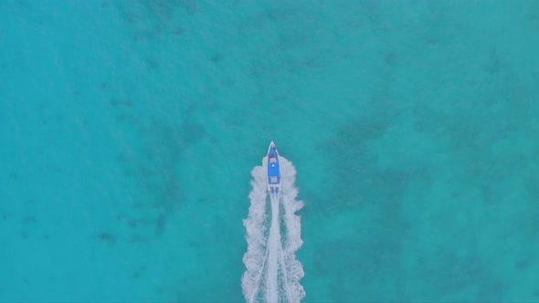 Aerial top down tracking of motorboat sailing on turquoise caribbean sea water, Dominican Republic