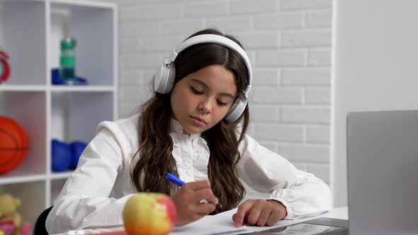 Serious Child in Headphones Writing Dictation at School Online Lesson with Laptop Quarantine Study