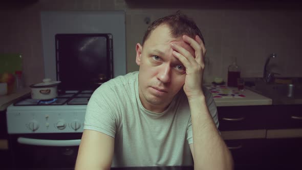 Portrait of a young man in depression at home at the table, camera movement