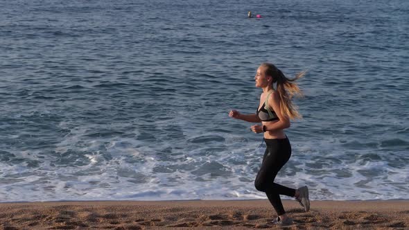 Blonde Female Runner Exercising on Sandy Beach