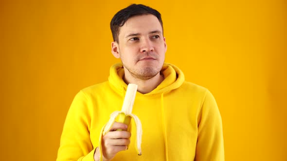 Young Man Eats Banana on Yellow Background