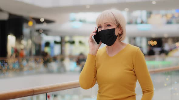 Caucasian Middleaged Woman in Medical Protective Mask Walking in Mall Speaking on Telephone