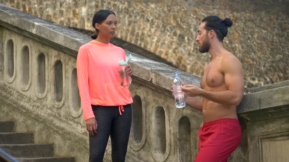 A couple take a break after a workout to drink water.