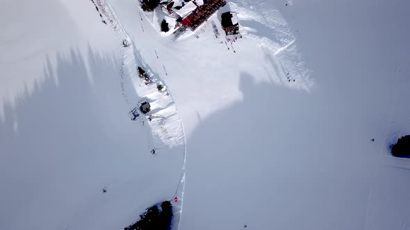 Aerial view of ski resort with people snowboarding down the hill. Stock footage. Flying over the ski