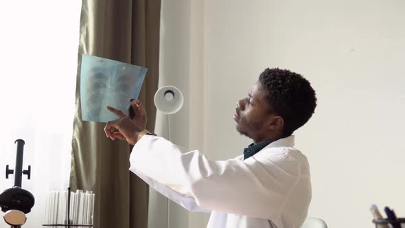 African American Male Doctor Working with the Xray at Desk