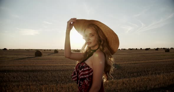 Seductive Girl Touches A Straw Hat At Sunset