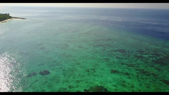 Aerial drone shot landscape of perfect shore beach voyage by blue water and white sandy background o