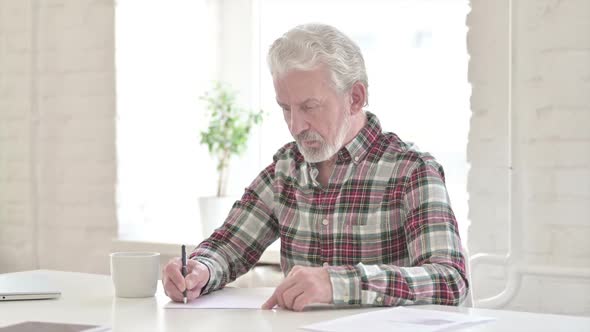 Serious Casual Old Man Doing Paperwork in Office