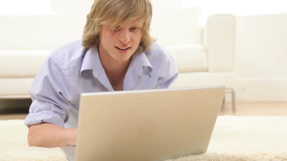 Young man laying on floor with laptop computer