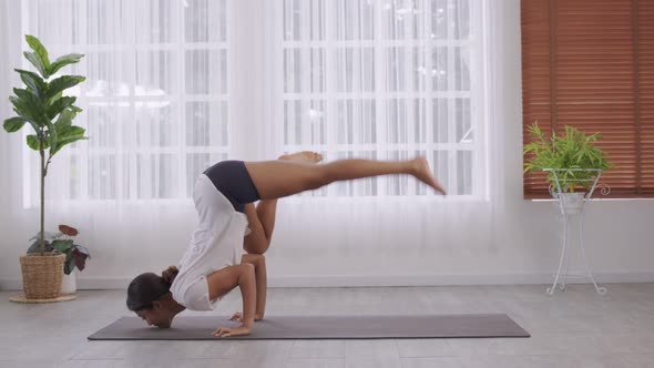 Yoga  Handstand Posture, Vrischikasana on mat, Asian woman in sportswear working out inside.