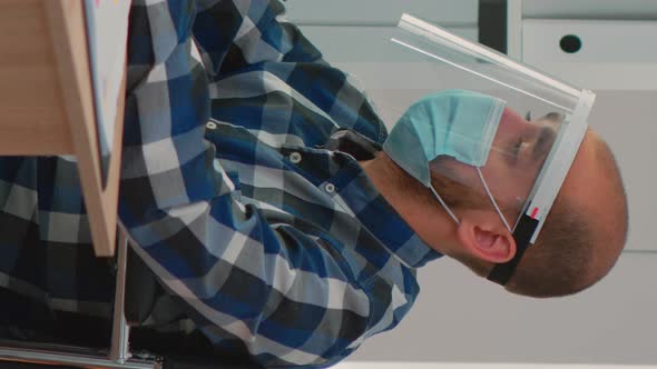 Disabled Businessman with Face Protection Working on Computer