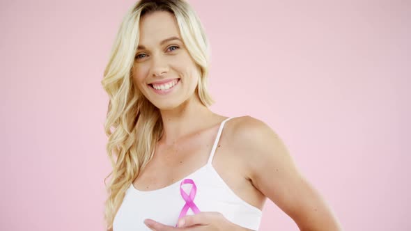 Smiling woman showing breast cancer awareness ribbon