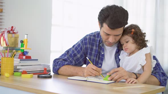 Portrait of young father teaching his cute little daughters' study. Children education