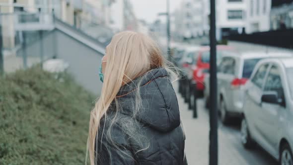 Female in a Medical Mask Escaping From Somebody on the Street.