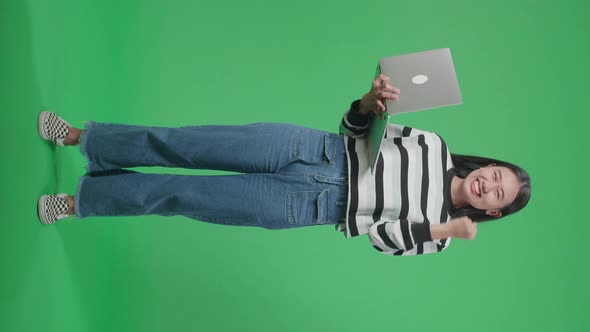 Full Body Of A Happy Asian Woman Celebrating While Using Computer On The Green Screen Background