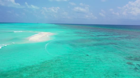 Aerial flying over landscape of tranquil shore beach time by shallow ocean with white sand backgroun