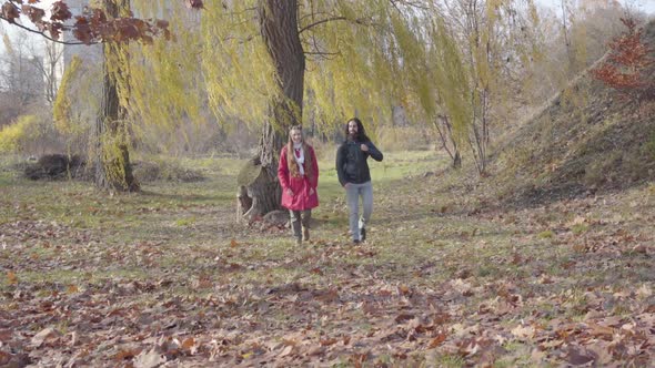 Joyful Middle Eastern Boyfriend and Caucasian Girlfriend Strolling Between Trees in Autumn Forest