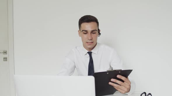 Confident Student with an Earset Passes the Exam Online Remotely on a Laptop