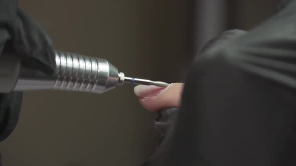 Manicurist Works with a Drill with Female Nails