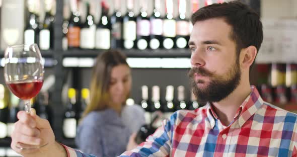 Side View of Professional Concentrated Sommelier Shaking Glass with Red Wine. Young Confident