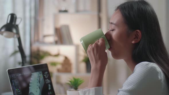 Close Up Of Asian Female Footwear Designer Drinking Coffee While Designing Shoe On A Laptop