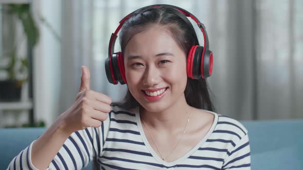 Woman Composer With Headphones Smiling And Showing Thumbs Up To Camera While Playing Guitar