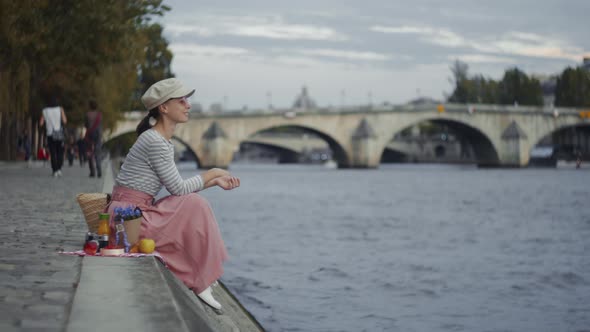 Smiling woman on a picnic by the Seine