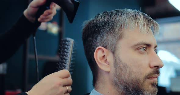 Adult Grayhaired Man is Dried and Combed His Hair at the Hair Salon