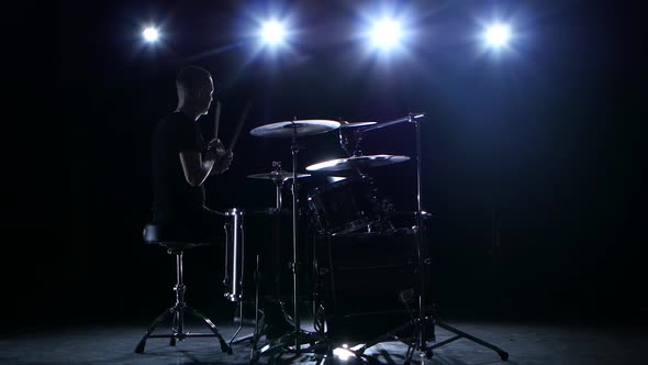 Drummer Plays the Melody on the Drums Energetically. Black Background. Back Light. Silhouette