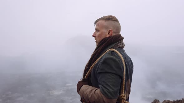 Man In Greatcoat Standing In Misty And Rocky Landscape