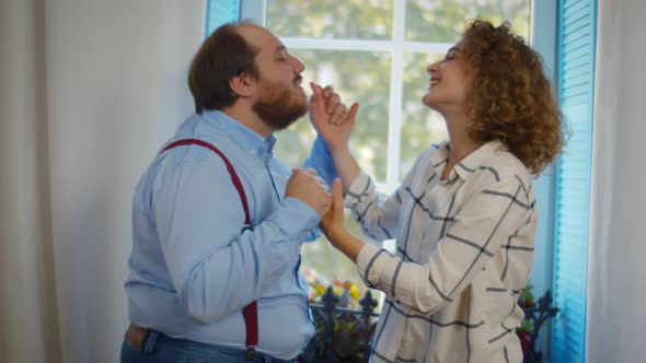 Happy Couple Dancing Together Standing in Living Room at Home