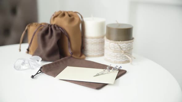 Beautiful female hand writing a wedding or holiday invitation on a bright white table with candles.