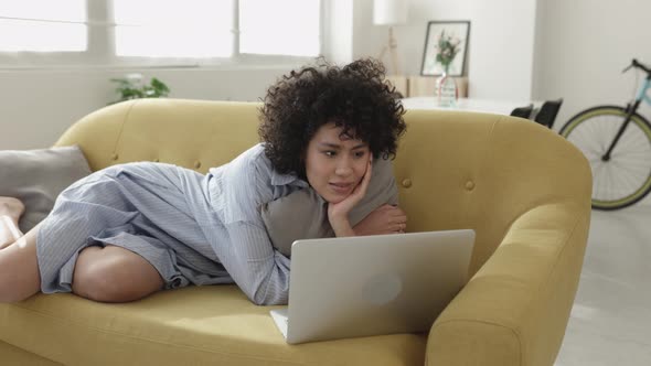 Young Adult Woman Watching Movies on Laptop Computer at Home