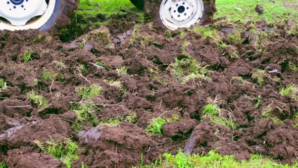 A Tractor Drives Across an Agricultural Field in a Garden Plot and Plows the Land with a Plow