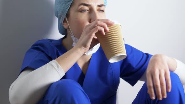 Tired Doctor or Nurse Drinking Takeaway Coffee
