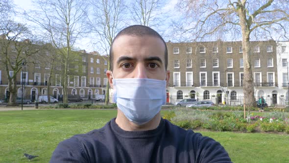 Young man portrait with face mask on - Man wearing a medical mask at park in